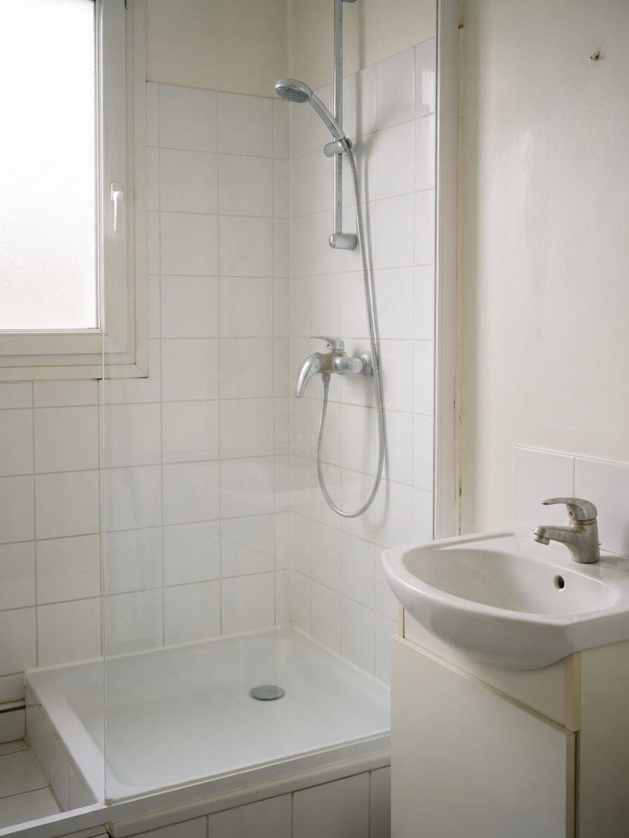 La même salle de bains nettoyée : paroi transparente, carrelage et joints propres, robinet net