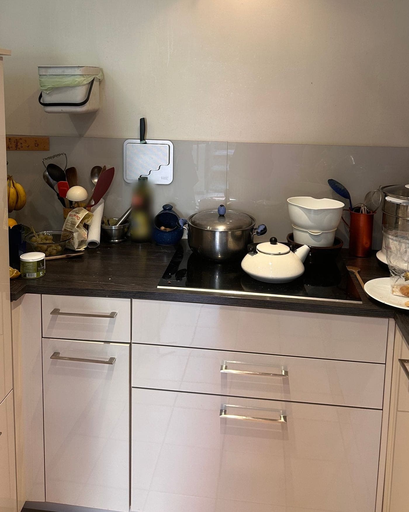 Plaque de cuisson entourée de casseroles, cuit-vapeur, assiette et ustensiles sur le plan de travail