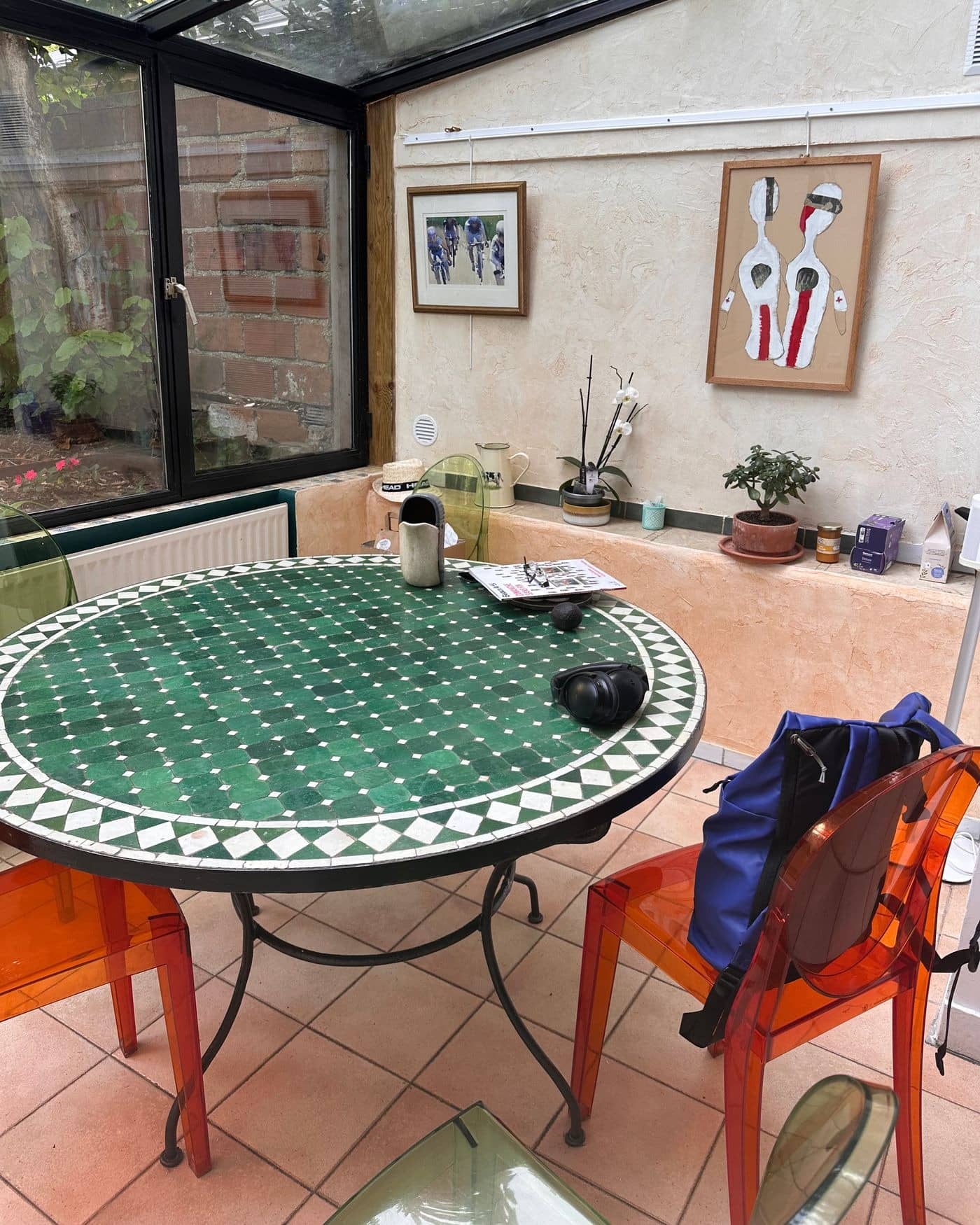 Véranda avant rangement : sac à dos, casque et magazine sur la table en mosaïque verte